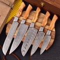 Set of six Damascus steel knives with wooden handles on a wooden block.
