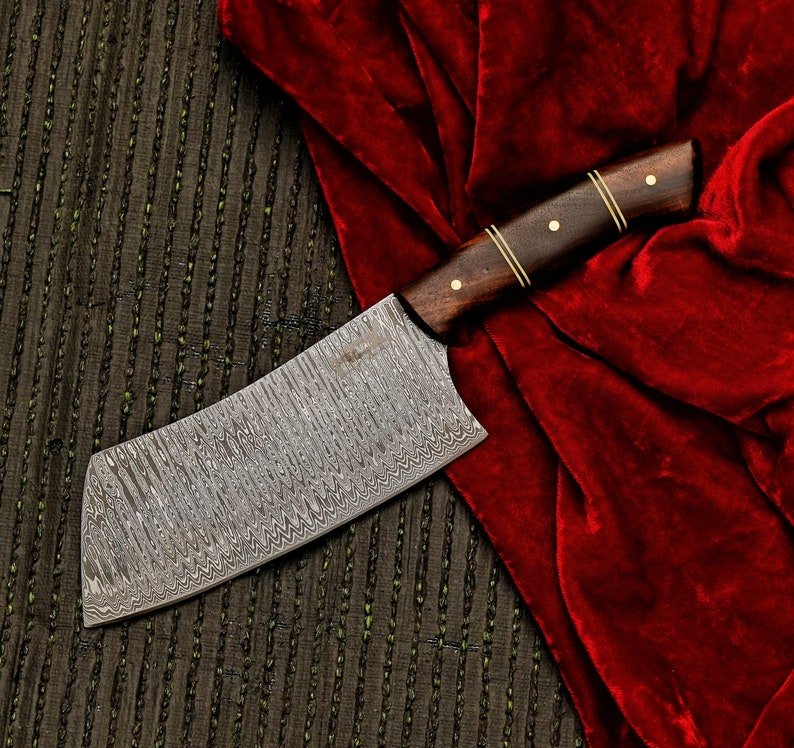 Damascus knife with wooden handle on a textured surface with red fabric