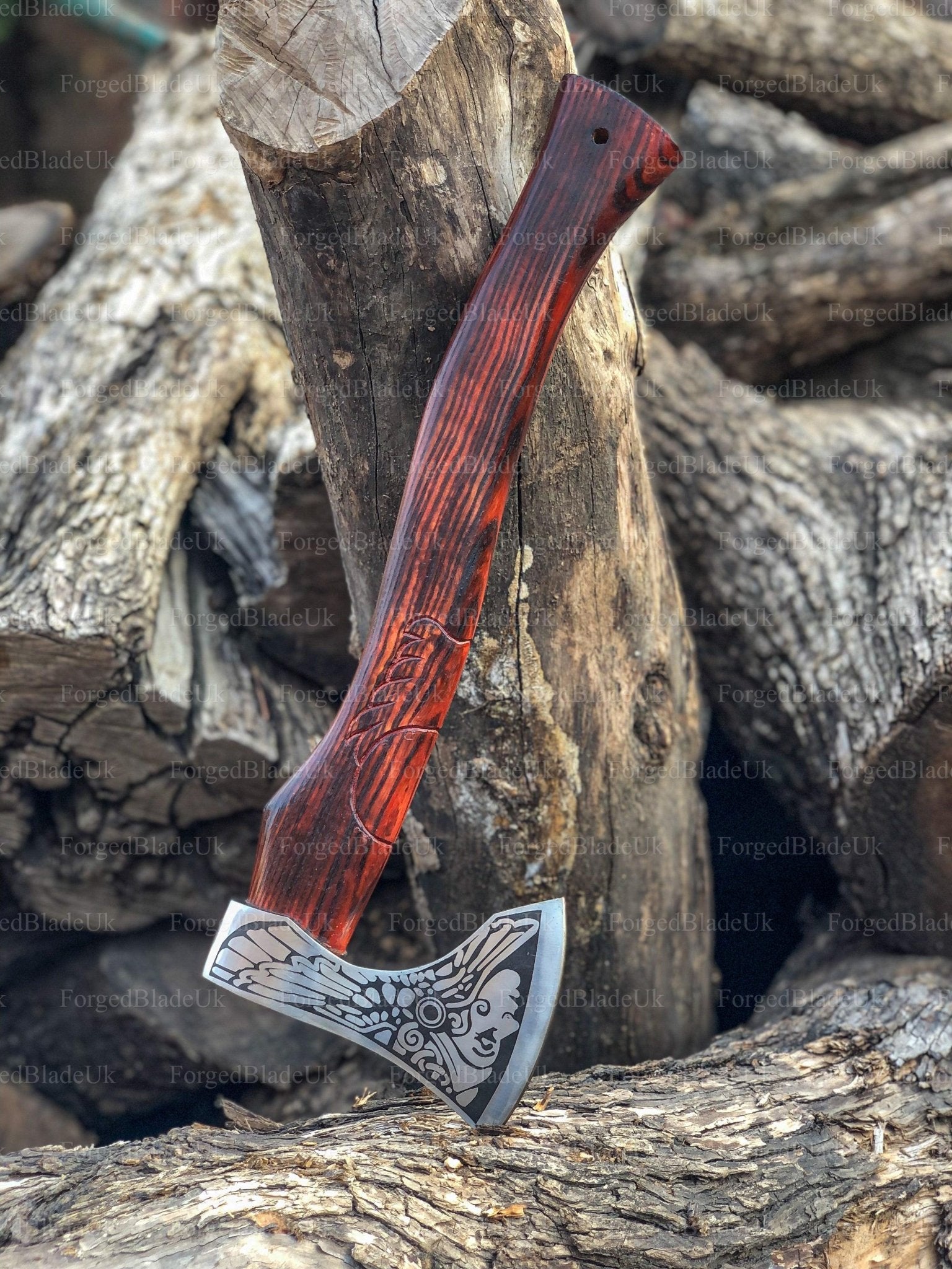 A handmade engraved axe with a wooden handle and a steel head, resting on a wooden stump with a logo inscribed on the axe head.