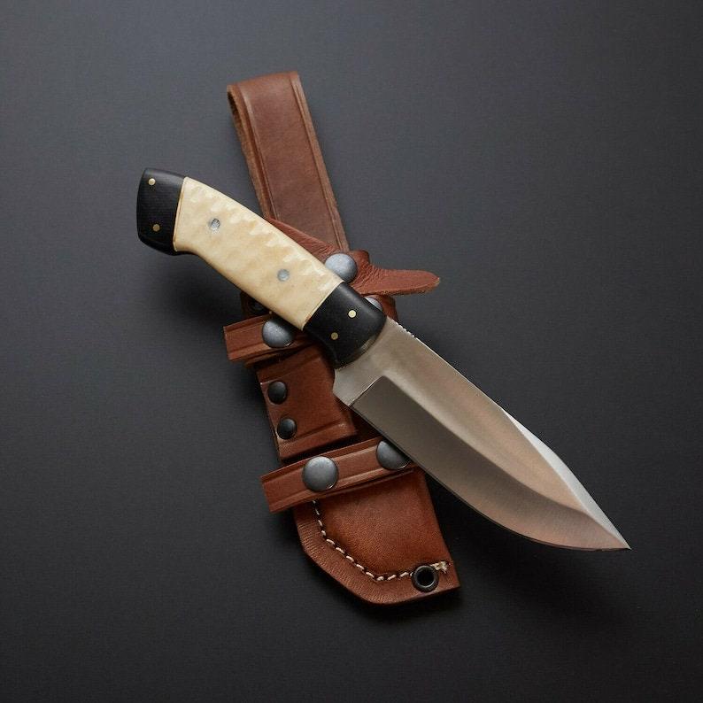 Handmade skinner knife with sharp curved steel blade and ergonomic handle for hunting and skinning tasks
