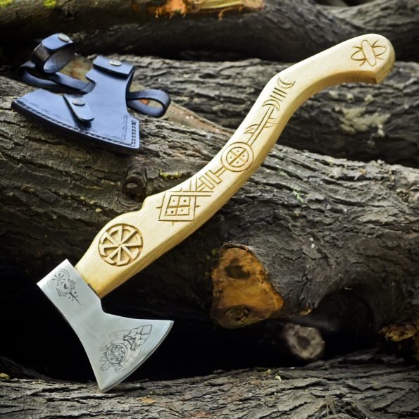 A corban steel axe with a wooden handle and a leather cover, placed on a bed of wooden logs.