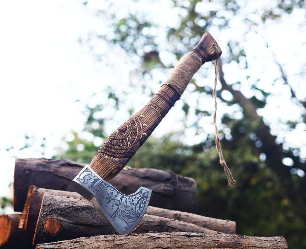 A Viking axe with a patterned blade and a wooden handle with a leather cover resting on a stack of wood.