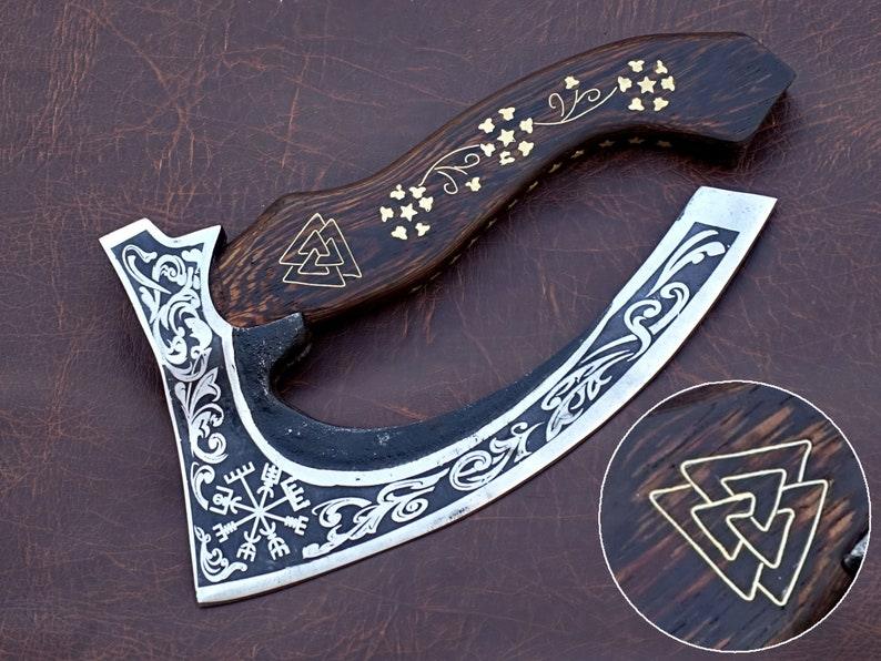 A pizza cutter with a wooden handle and a steel blade featuring intricate engravings.